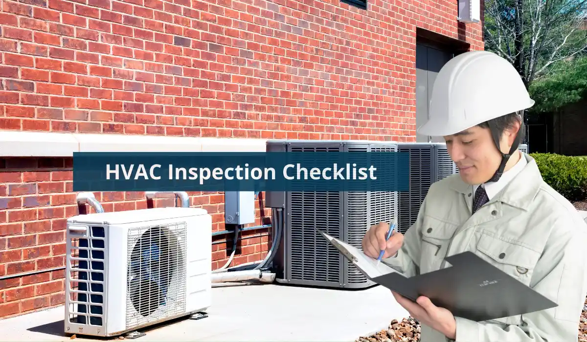 A person in a hard hat reviews an HVAC inspection checklist next to two air conditioning units against a brick wall.